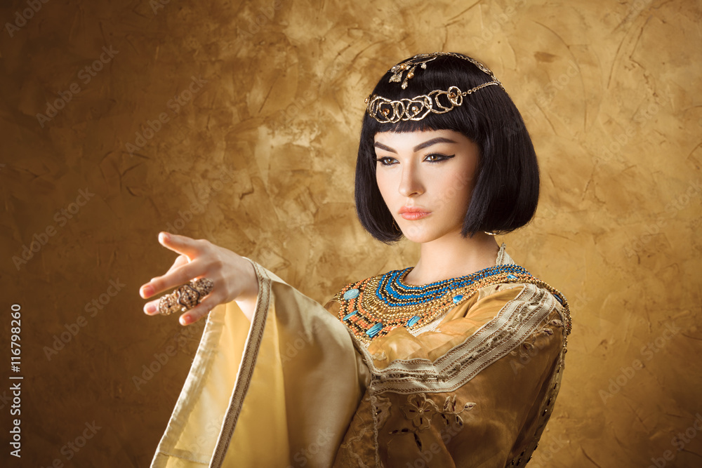 Beautiful Egyptian woman like Cleopatra pointing finger away on golden ...