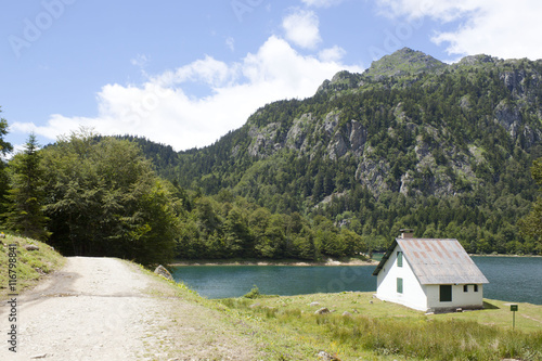 House in front of a lake and mountains with pine trees