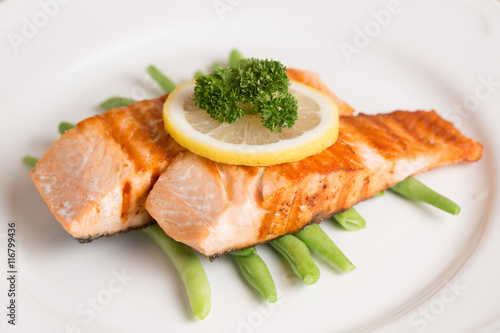 Grill salmon steak serve with lemon and green beans on wooden table