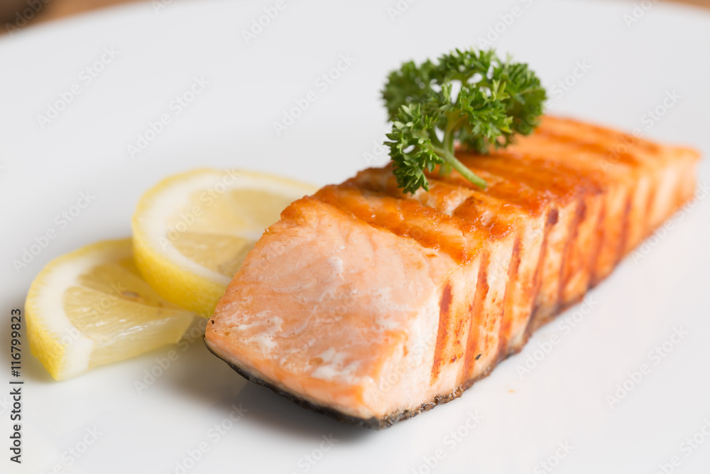Grill salmon steak serve with lemon and colorful salad on wooden table Grill salmon steak serve with lemon and colorful salad on wooden table