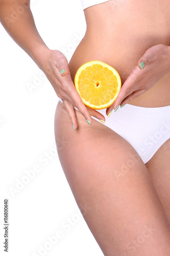 Close up of a fit woman carrying half an orange on white backgro