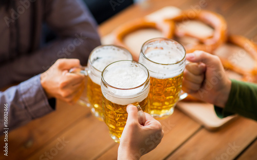 close up of hands with beer mugs at bar or pub photo