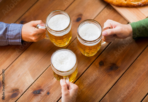 close up of hands with beer mugs at bar or pub