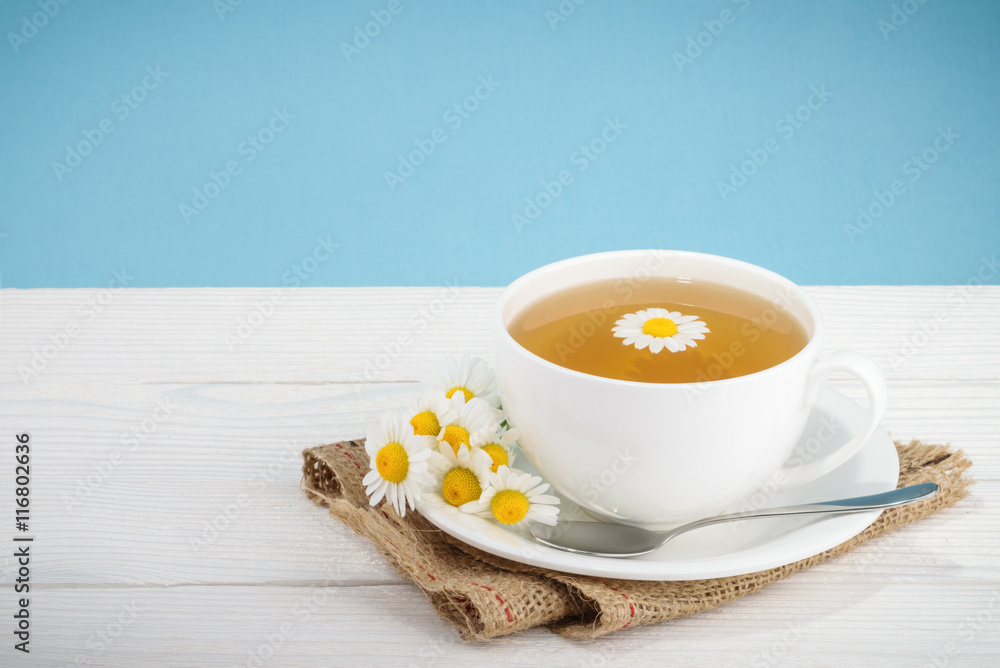 Cup of tea and chamomiles on wooden background Cup of tea and chamomiles on wooden background