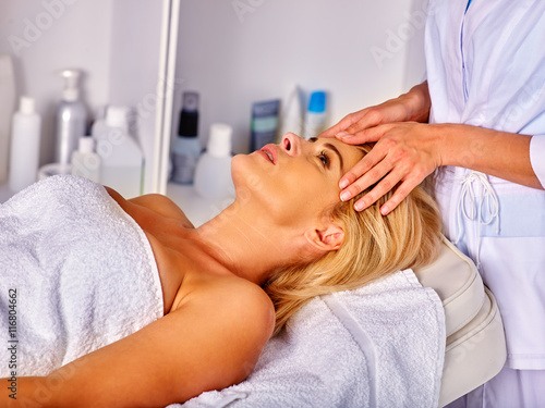 Woman middle-aged take face and neck massage in spa salon. Anti-aging massage in modern spa salon.