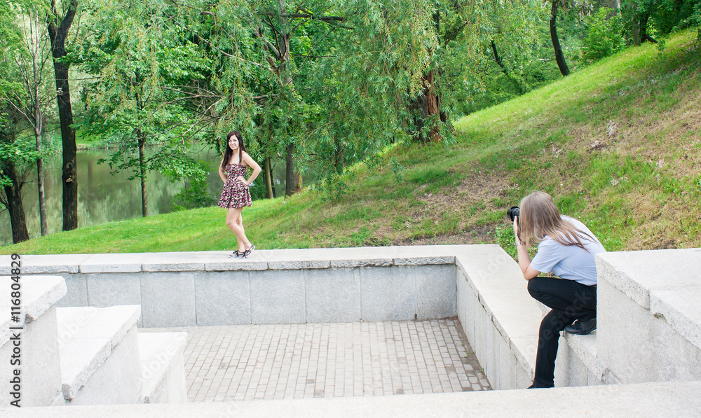 photographer takes a woman standing on the stairs in the park