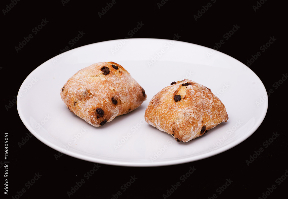 Two sandwich buns with raisons on white plate Two sandwich buns with raisons on white plate