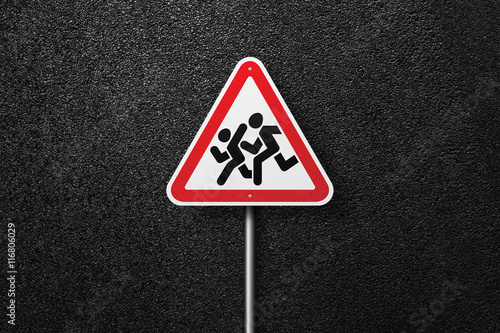 Road sign triangular shape with a picture of a children on a background of asphalt. The texture of the tarmac, top view. © srzaitsev