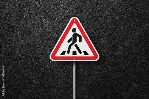 Road sign triangular shape with a picture of a pedestrian on a background of asphalt. The texture of the tarmac, top view. © srzaitsev