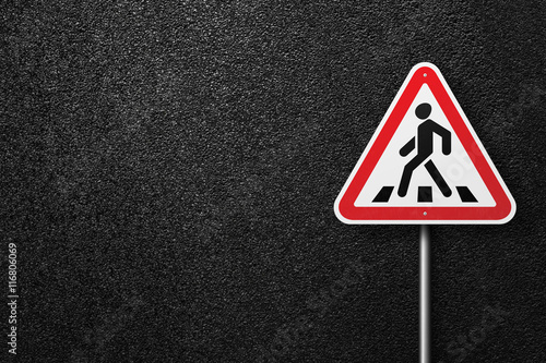 Road sign triangular shape with a picture of a pedestrian on a background of asphalt. The texture of the tarmac, top view.
