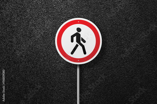 Road sign circular shape with a picture of the pedestrian on a background of asphalt. The texture of the tarmac, top view.