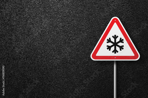 Cuadro en lienzo Road sign triangular shape with a picture of snowflakes on a background of asphalt