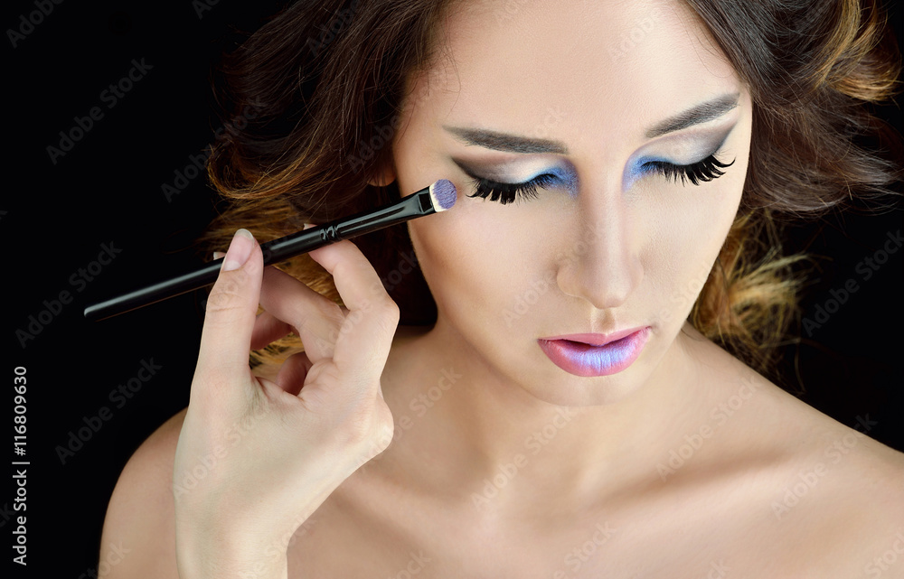 Obraz premium Wedding makeup artist making a make up for bride. Beautiful sexy model girl indoors. Beauty woman with curly hair. Female portrait. Bridal morning of a cute lady. Close-up hands near face