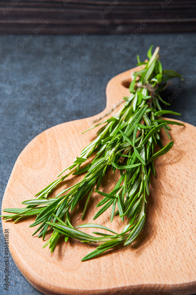 Bunch of fresh rosemary sprigs on a bamboo chopping board Bunch of fresh rosemary sprigs on a bamboo chopping board