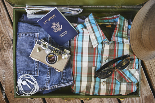 vacation items including suitcase, clothing,camera,passport, and sunglasses
