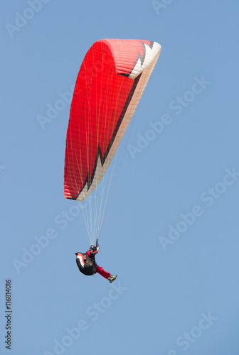 Man flying on a red paraglider it the evening