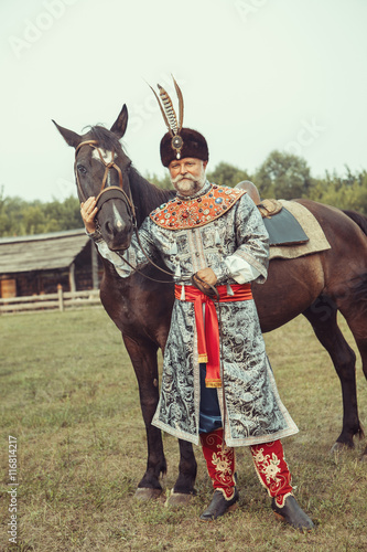 King dressed in medieval costume is stroking his horse 