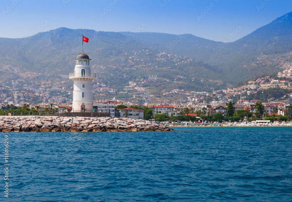 Lighthouse in Alanya, Antalya district, Turkey, Asia. View on city from boat. Popular tourist destination. Clear water in sunny day.