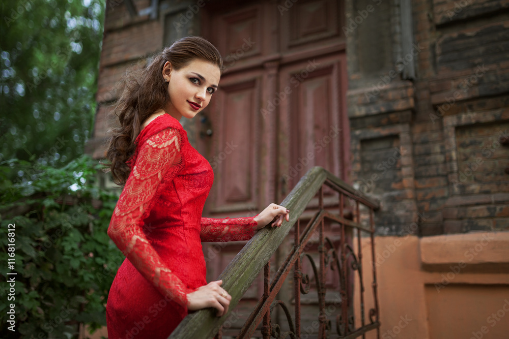 Beautiful fashion woman posing in red dress with creative hairstyle. Trendy urban portrait on green background. Beautiful fashion woman posing in red dress with creative hairstyle. Trendy urban portrait on green background.