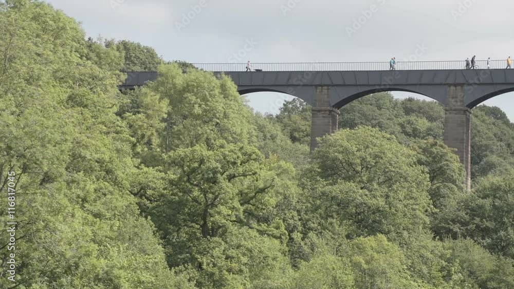 A shot of a barge and pedestrians traveling over the world famous Pontcysyllte Aqueduct on the Llangollen Canal between Wales and England. A shot of a barge and pedestrians traveling over the world famous Pontcysyllte Aqueduct on the Llangollen Canal between Wales and England.