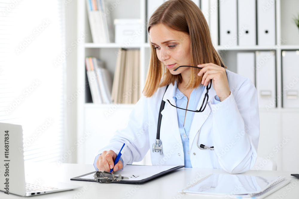 Female doctor writing a medical prescription at clipboard Female doctor writing a medical prescription at clipboard