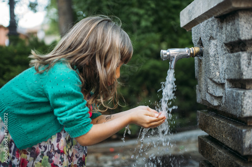 Fotografie girl drinking water from a fountain