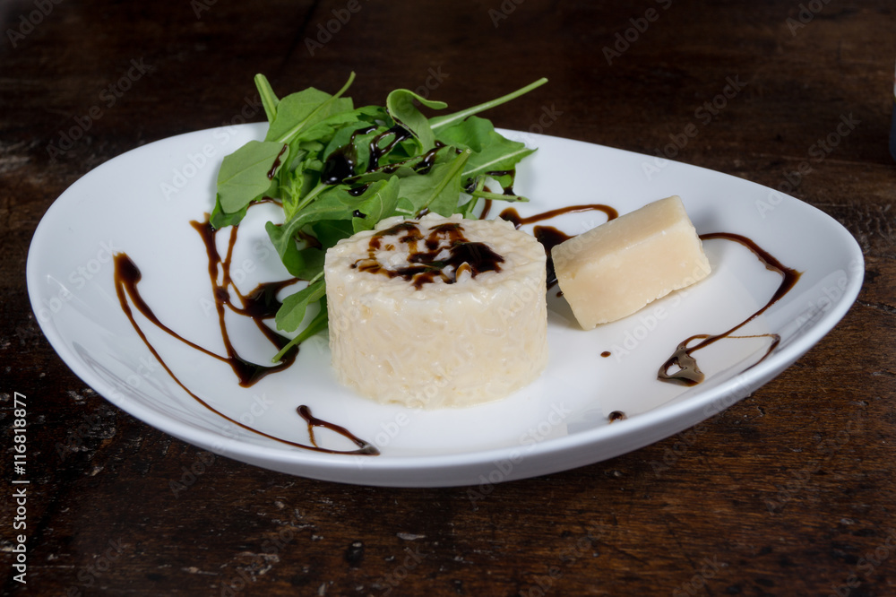 Risotto ai formaggi in primo piano su piatto con rucola e aceto balsamico Risotto ai formaggi in primo piano su piatto con rucola e aceto balsamico