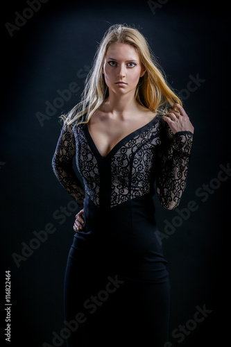 blonde girl on a black background in a dark guipure dress