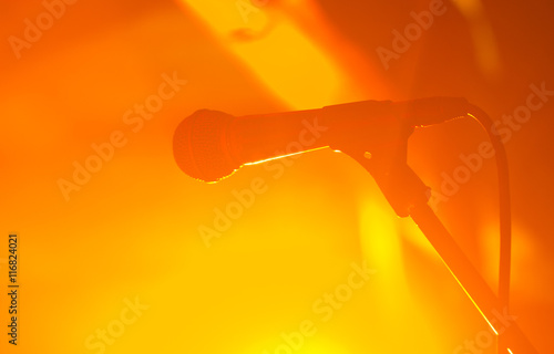 silhouette of wired microphone against orange concert gig background