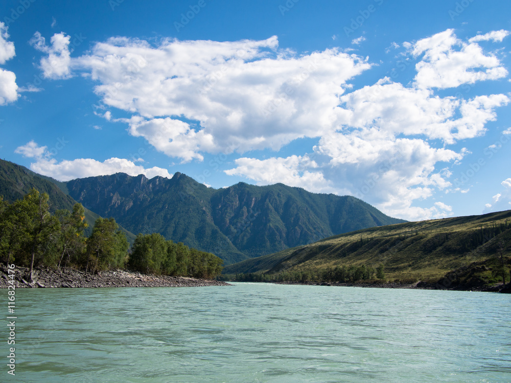 View of the wide river with mountains and trees against the sky with clouds