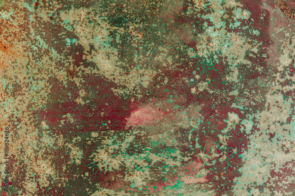 Old rusty metal surface is covered with several layers of peeling paint of different colors. background