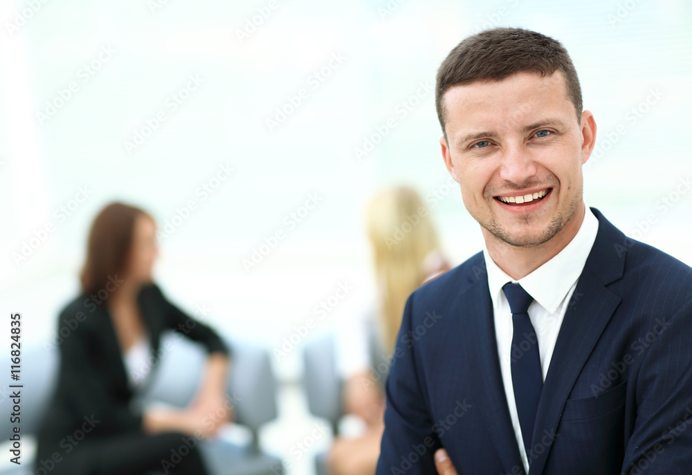 Successful business man standing with his staff in background at Successful business man standing with his staff in background at
