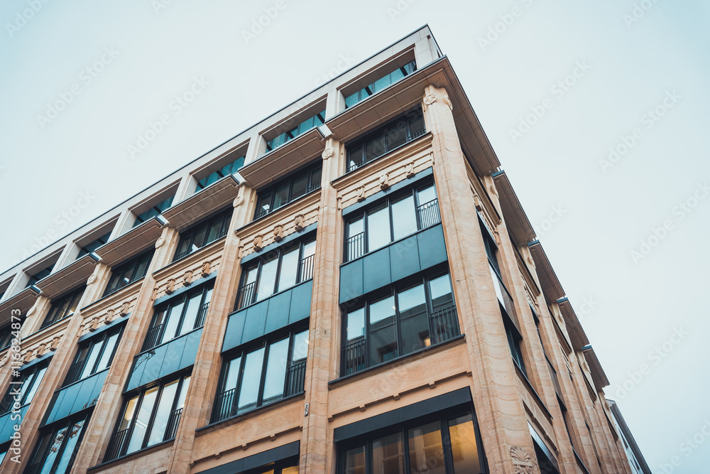 Tall sandstone building with reflective windows