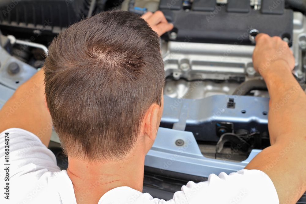 Auto mechanic checking the condition of car engine. Man working on car in garage Auto mechanic checking the condition of car engine. Man working on car in garage