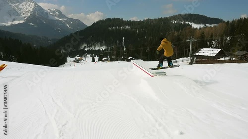 snowboard freestyle slow motion,following snowboarder jumping on boardslide steadicam photo