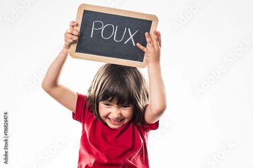 furious young child holding a school slate against head lice photo