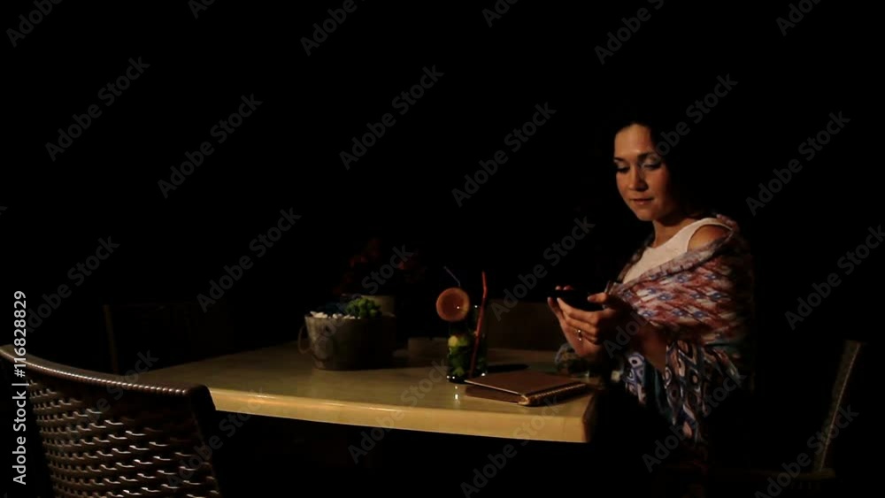 Happy brunette girl talking to friend on phone in beach cafe, relaxing evening Happy brunette girl talking to friend on phone in beach cafe, relaxing evening