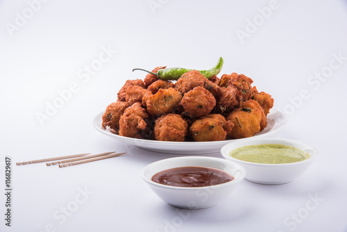 Delicious Tasty and Yummy Indian Moong Dal vada or moong dal pakoda or moong vade or Pakora (Fritter) with fried green chilli, red and green hot sauce. photo