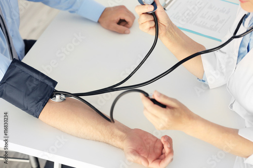 Female doctor measuring man blood pressure with tonometer