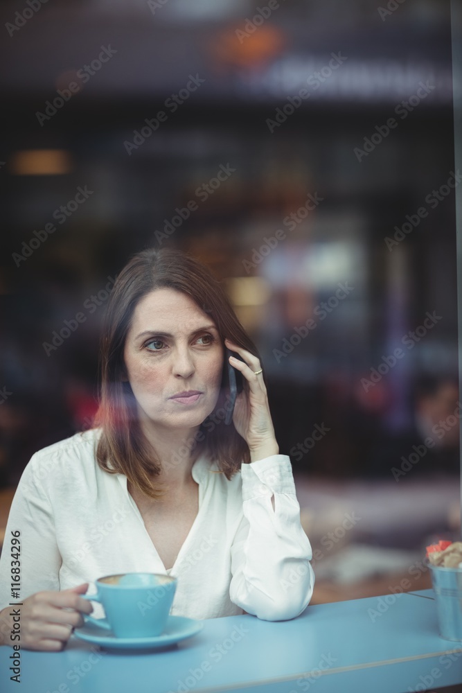 Woman holding coffee cup and talking on mobile phone Woman holding coffee cup and talking on mobile phone
