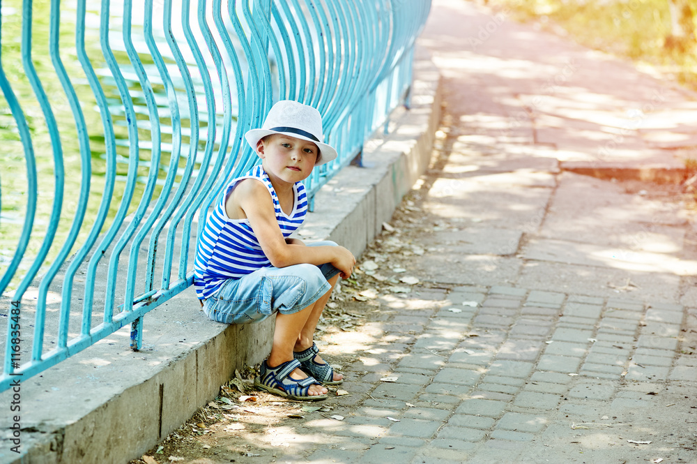 Portrait of a beautiful boy in a city Park . Dressed in a nautical style . Portrait of a beautiful boy in a city Park . Dressed in a nautical style .