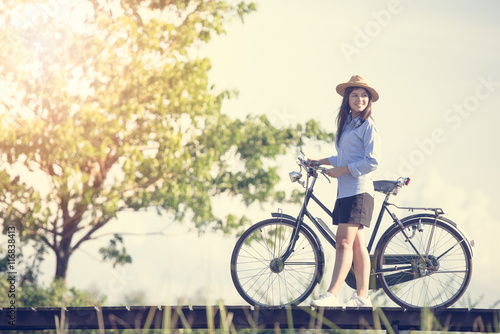 Woman with vintage bike on the bridge. Vintage tone filter.