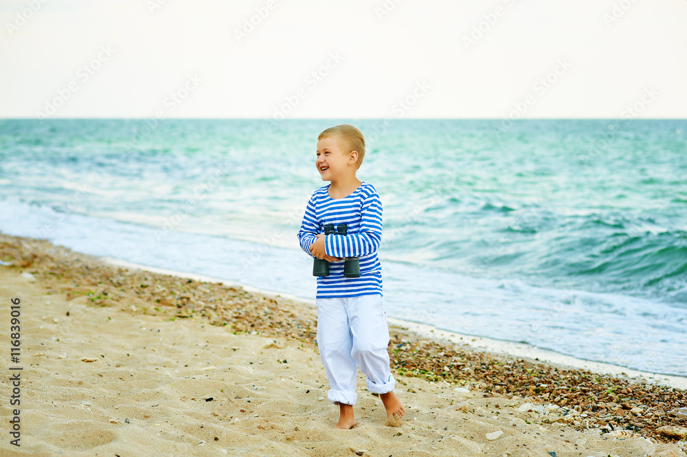 The little boy in the vest with the binoculars , walks on the beach The little boy in the vest with the binoculars , walks on the beach