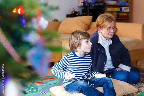 Little kid boy and grandmother playing video game console