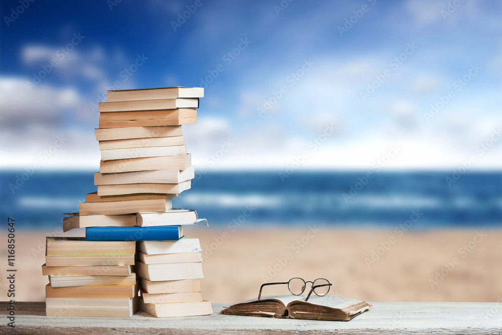 Naklejka premium Stack of Travel Guides before a empty Beach