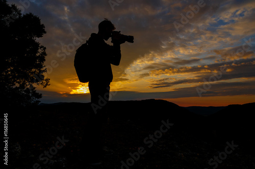 silhouette of photographer taking picture of landscape during su