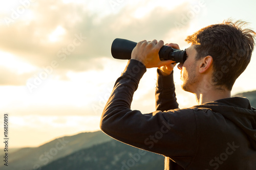 Young Man use of the binocular at forest