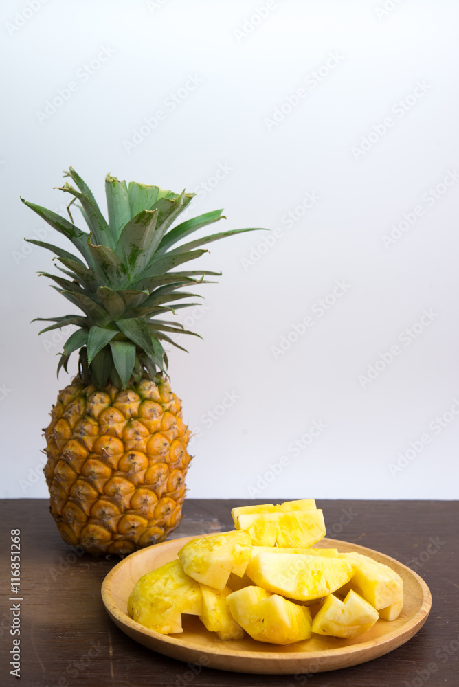 Pineapple fruit cut on wooden plate on white background Pineapple fruit cut on wooden plate on white background