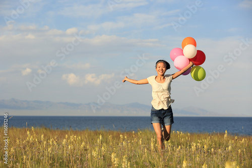 cheering young asian woman on grassland with colored balloons © lzf