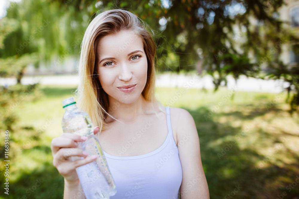close-up portrait of beautiful young blond woman in white blouse at park.woman holding a water bottle close-up portrait of beautiful young blond woman in white blouse at park.woman holding a water bottle